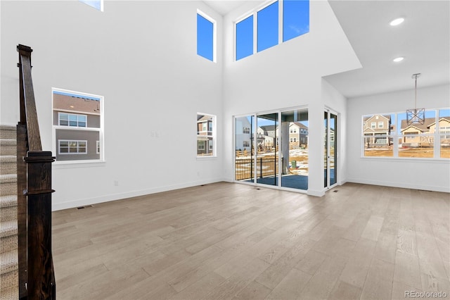 unfurnished living room featuring visible vents, baseboards, wood finished floors, stairs, and recessed lighting