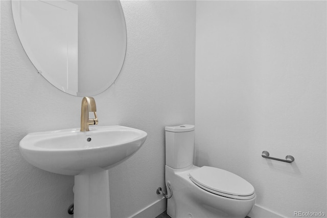 bathroom featuring baseboards, a sink, and toilet