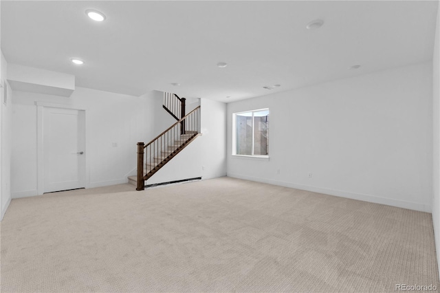 unfurnished room featuring recessed lighting, light carpet, baseboards, and stairs