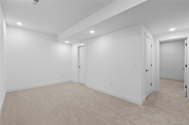 basement featuring light carpet, baseboards, visible vents, and recessed lighting