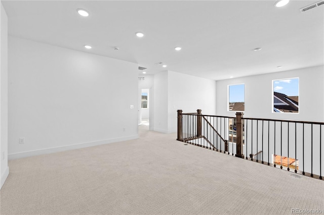 unfurnished room with baseboards, visible vents, light colored carpet, and recessed lighting