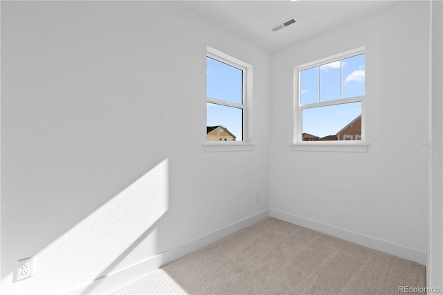 carpeted spare room featuring baseboards and visible vents