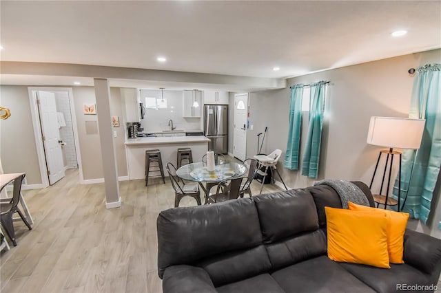 living room featuring sink and light hardwood / wood-style flooring