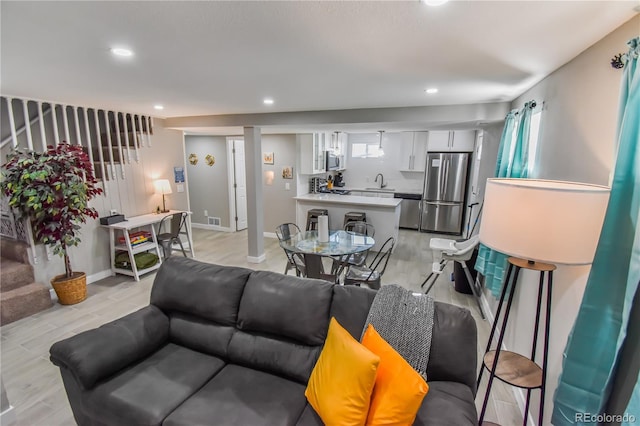 living room featuring sink and light hardwood / wood-style flooring