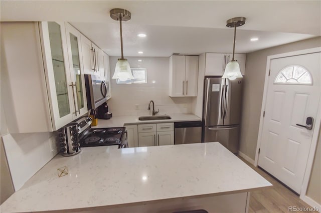 kitchen with white cabinetry, appliances with stainless steel finishes, sink, and pendant lighting