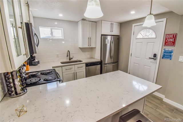 kitchen featuring pendant lighting, appliances with stainless steel finishes, kitchen peninsula, and sink