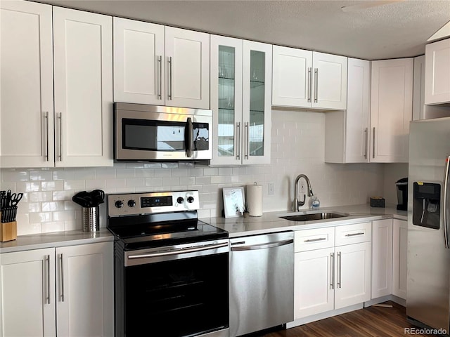 2200 W Moffat Pl, Denver, CO 80221 - kitchen featuring appliances with stainless steel finishes, a sink, white cabinetry, decorative backsplash, and a textured ceiling