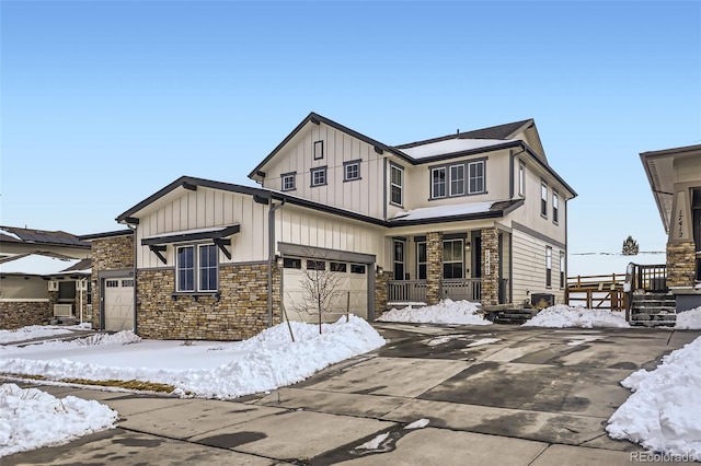 view of front of house with concrete driveway, stone siding, an attached garage, covered porch, and board and batten siding