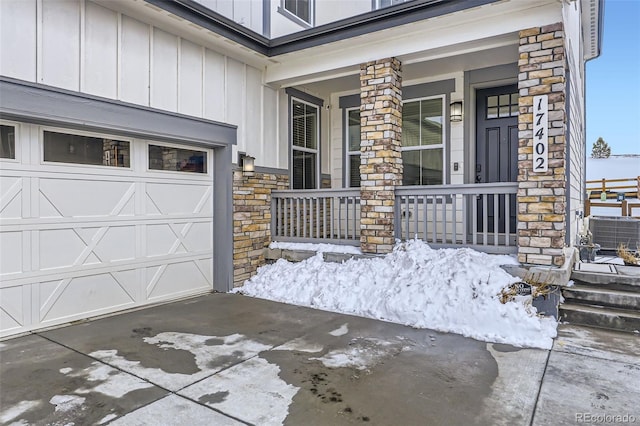 view of exterior entry featuring board and batten siding, stone siding, a porch, and concrete driveway