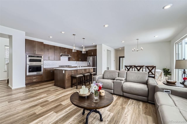 living room featuring a chandelier, light wood finished floors, and recessed lighting