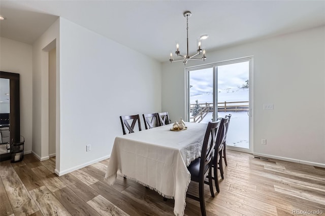 dining space featuring baseboards, an inviting chandelier, and wood finished floors