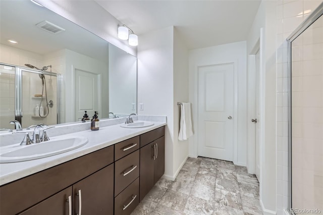 bathroom with double vanity, a shower stall, visible vents, and a sink