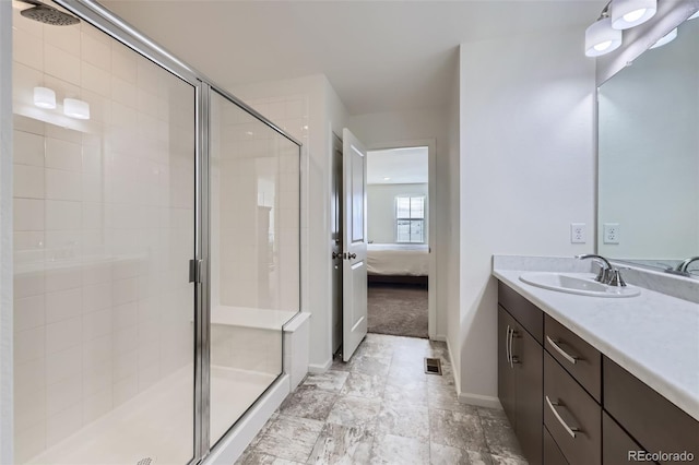 ensuite bathroom with visible vents, connected bathroom, a shower stall, vanity, and baseboards