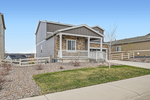 5256 Trails Edge Ln, Castle Rock, CO 80104 - view of front facade featuring a front lawn, fence, covered porch, stone siding, and board and batten siding