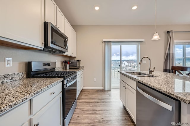 5256 Trails Edge Ln, Castle Rock, CO 80104 - kitchen with light stone countertops, white cabinetry, a sink, light wood finished floors, and appliances with stainless steel finishes