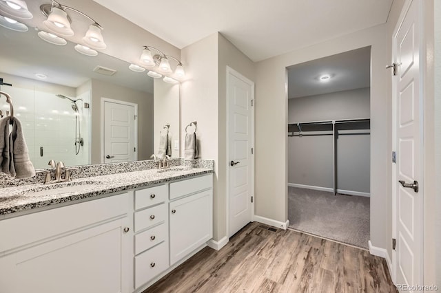 5256 Trails Edge Ln, Castle Rock, CO 80104 - full bathroom with double vanity, a shower stall, wood finished floors, a sink, and baseboards