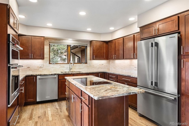 kitchen featuring tasteful backsplash, stainless steel appliances, sink, light hardwood / wood-style flooring, and a kitchen island