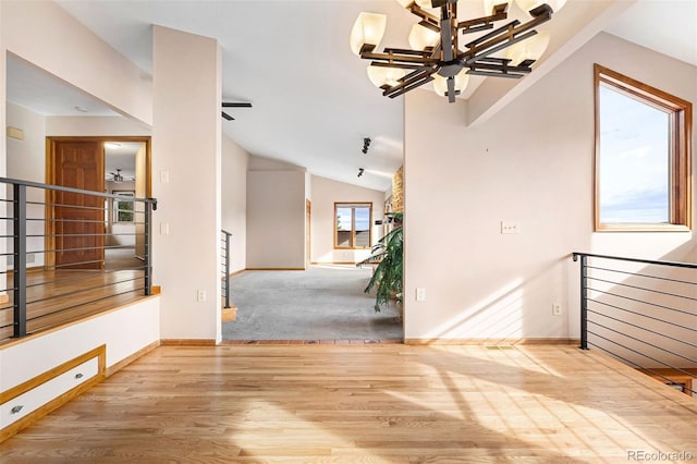 interior space with vaulted ceiling, ceiling fan with notable chandelier, and light wood-type flooring