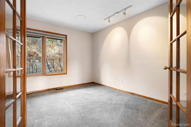 carpeted empty room featuring french doors and track lighting