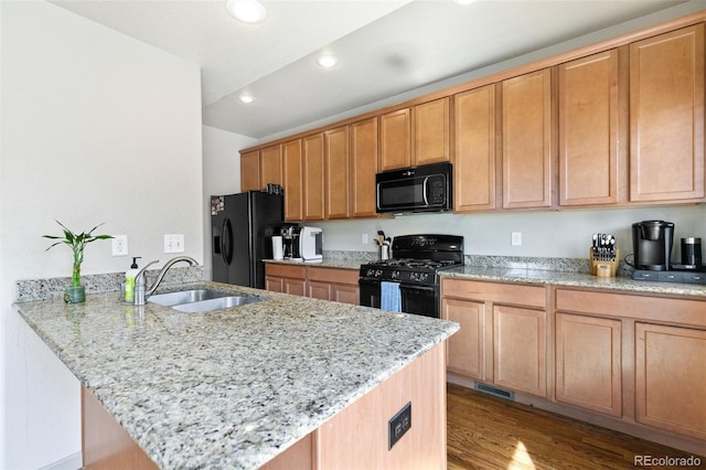 kitchen with light stone countertops, black appliances, sink, and kitchen peninsula