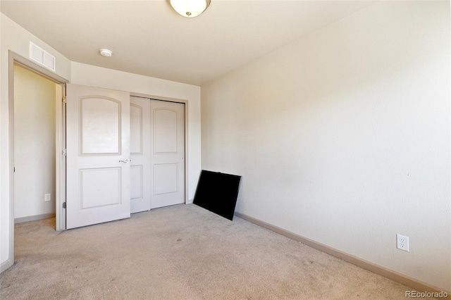 unfurnished bedroom with light carpet and a closet