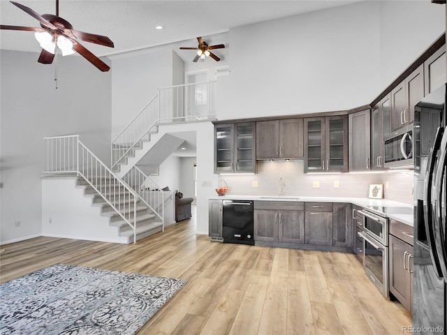 655 Gooseberry Ct, Lafayette, CO 80026 - kitchen featuring appliances with stainless steel finishes, ceiling fan, light wood-style floors, a high ceiling, and dark brown cabinets