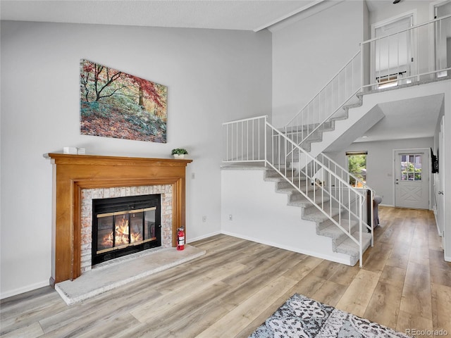 655 Gooseberry Ct, Lafayette, CO 80026 - unfurnished living room featuring stairs, wood finished floors, high vaulted ceiling, and a glass covered fireplace