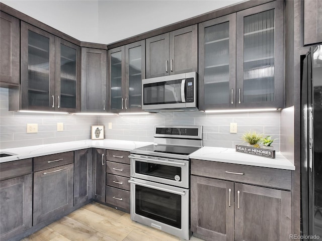 655 Gooseberry Ct, Lafayette, CO 80026 - kitchen featuring stainless steel appliances, tasteful backsplash, dark brown cabinets, and glass insert cabinets
