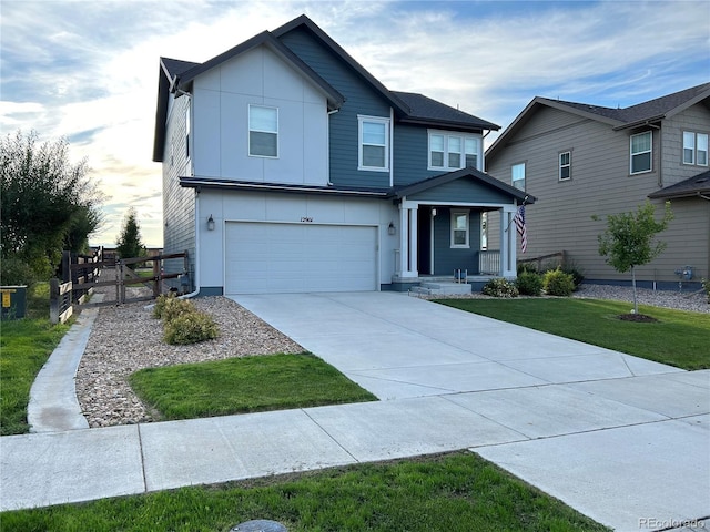 12901 Crane River Dr, Longmont, CO 80504 - view of front of property featuring driveway, a front yard, a garage, fence, and covered porch