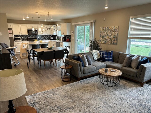 12901 Crane River Dr, Longmont, CO 80504 - living room featuring dark wood-style flooring, recessed lighting, and an inviting chandelier