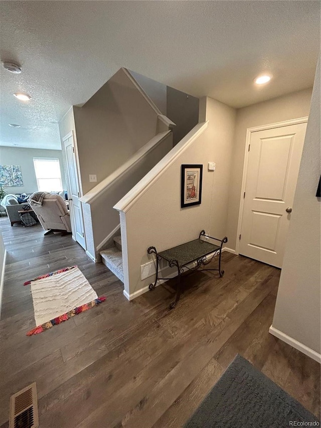 12901 Crane River Dr, Longmont, CO 80504 - hallway with visible vents, baseboards, dark wood finished floors, a textured ceiling, and stairs