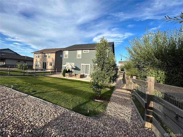 12901 Crane River Dr, Longmont, CO 80504 - rear view of property featuring a fenced backyard, a patio, and a lawn