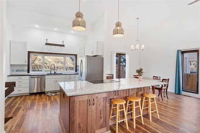 kitchen featuring white cabinets, stainless steel appliances, light stone counters, and sink