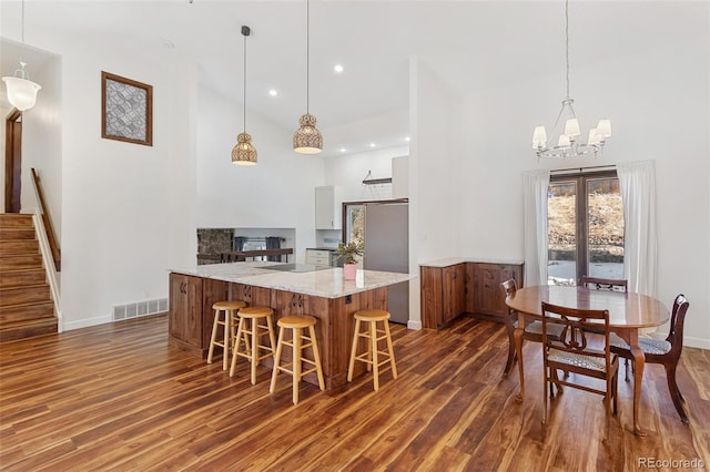 kitchen featuring white cabinets, decorative light fixtures, dark hardwood / wood-style flooring, and light stone counters