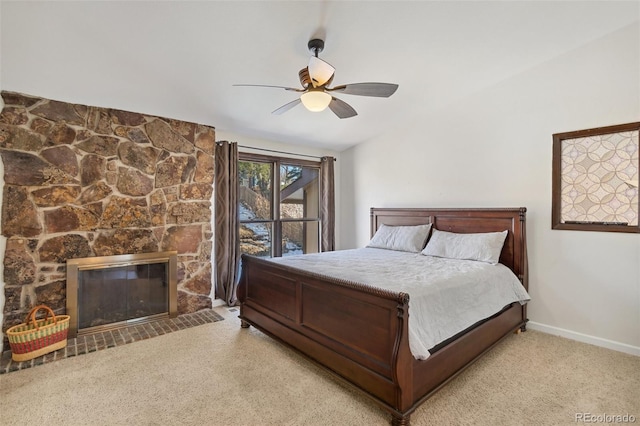 bedroom featuring ceiling fan, a stone fireplace, and light carpet