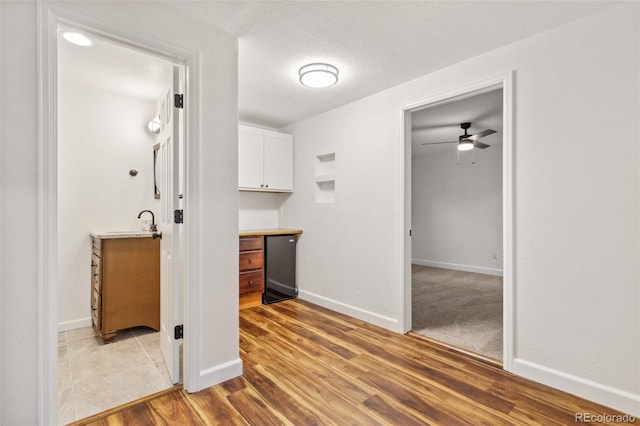 interior space featuring ceiling fan, dishwasher, a textured ceiling, white cabinets, and light wood-type flooring