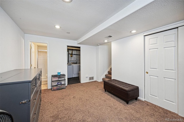 living area featuring dark colored carpet, washer and clothes dryer, and a textured ceiling