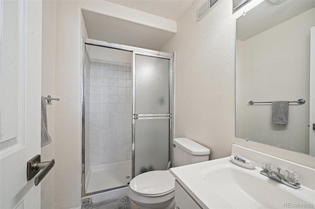 bathroom featuring a textured ceiling, a shower with door, vanity, and toilet