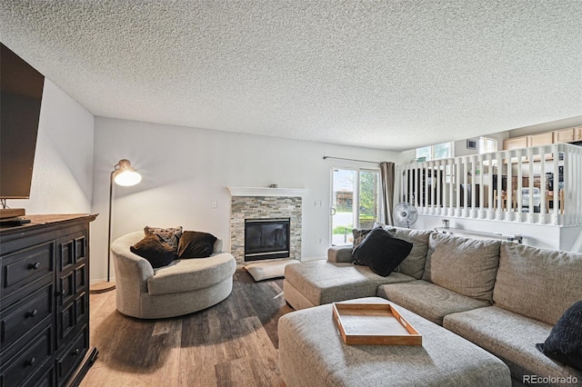 living room featuring a stone fireplace, hardwood / wood-style flooring, and a textured ceiling