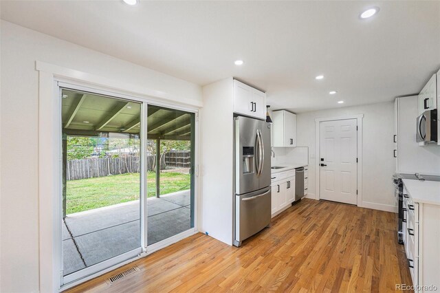 2280 Sherrelwood Dr, Denver, CO 80221 - kitchen featuring stainless steel appliances, light wood-style flooring, recessed lighting, white cabinetry, and light countertops