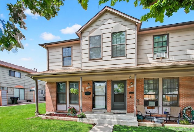 3947 W Ohio Ave, Denver, CO 80219 - traditional home featuring covered porch, brick siding, a front yard, and cooling unit