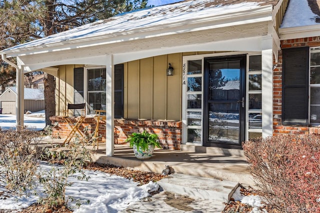 snow covered property entrance with a porch