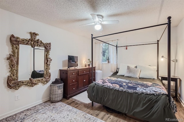 bedroom featuring light wood-type flooring, ceiling fan, and a textured ceiling