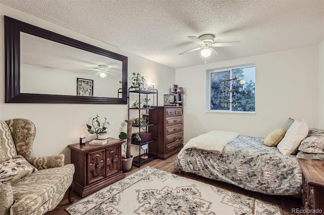 bedroom with a textured ceiling, ceiling fan, and hardwood / wood-style floors