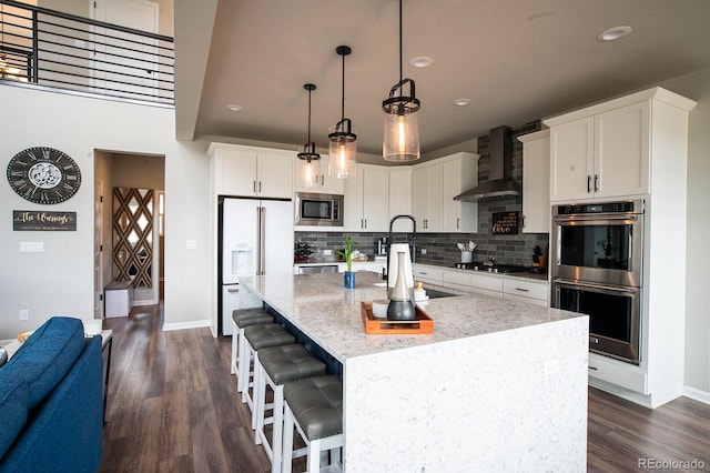 695 Simmental Loop, Castle Rock, CO 80104 - kitchen featuring stainless steel appliances, wall chimney exhaust hood, decorative backsplash, dark wood-type flooring, and recessed lighting