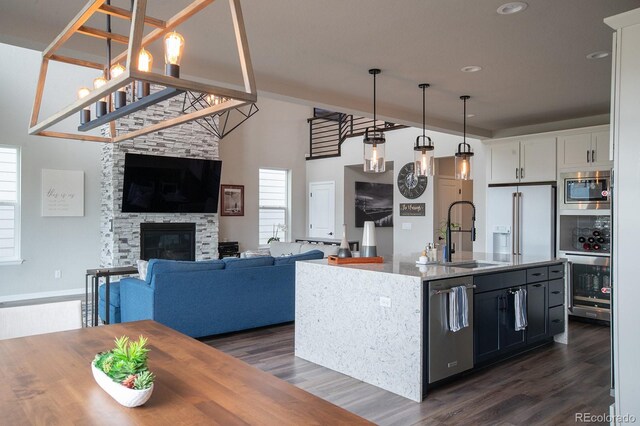 695 Simmental Loop, Castle Rock, CO 80104 - kitchen featuring a sink, appliances with stainless steel finishes, dark wood-style floors, light stone countertops, and hanging light fixtures