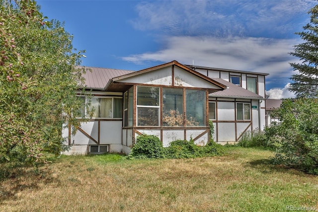 rear view of house with a lawn and a sunroom