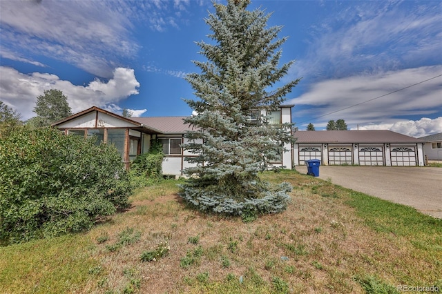 view of front of home with a garage, driveway, metal roof, and a front yard