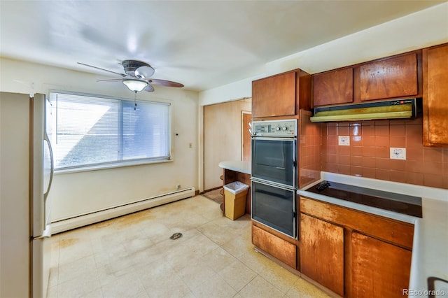 kitchen with tasteful backsplash, light countertops, baseboard heating, brown cabinetry, and freestanding refrigerator