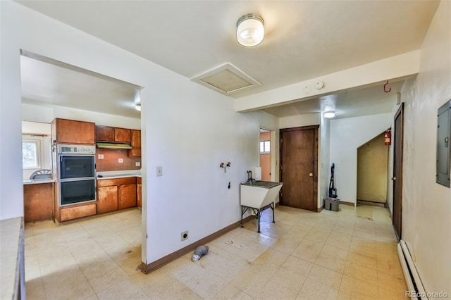 kitchen featuring a baseboard radiator, backsplash, and double oven